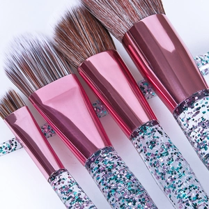 Macro detail of eye makeup brushes with glitter sand handles and pink metal ferrule