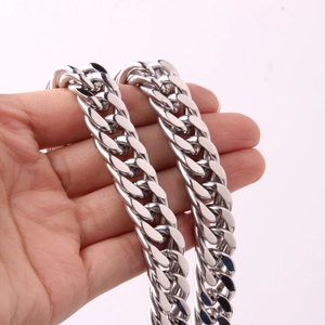 Close-up of polished silver double buckle cuban link chain held in hand for scale