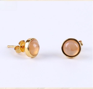 Macro detail of peach moonstone earrings with gold-plated base and sparkling crystals