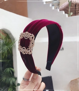 Close-up of a burgundy velvet headband with pleated texture and sparkling rhinestone buckle