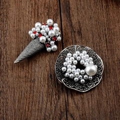 Detailed close-up of retro ice cream cone and floral hollow brooches with pearls