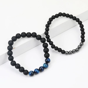 Detailed view of matte black beaded bracelets with blue tiger eye stones on white steps