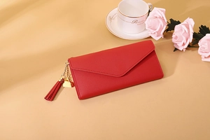 Detail of red envelope wallet with gold heart pendant and leather fringe tassel