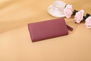 Detail view of a long purple leather wallet with elegant fringe zipper and rose decor