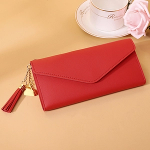 Close-up of red faux leather wallet with metallic heart pendant and tassel detail