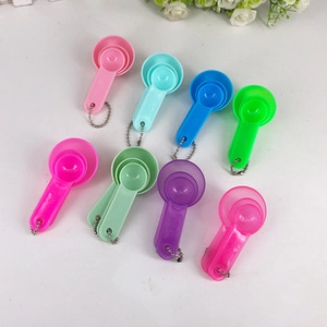 Set of colorful plastic measuring spoons in pink, blue, green, and purple with chains