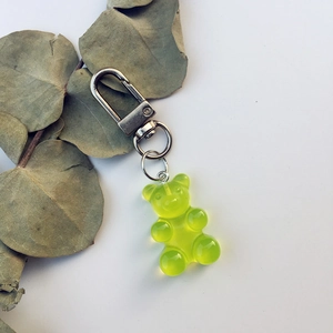 Detail of neon green resin gummy bear keychain with silver metal clasp on eucalyptus