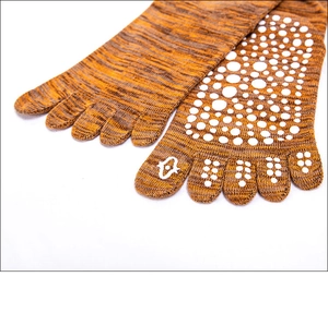 Close-up of five-toe yoga socks showing orange knit texture and white anti-slip silicone dots