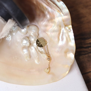 Detail of 14K gold plated chain ring with good luck charm inside a pearl shell