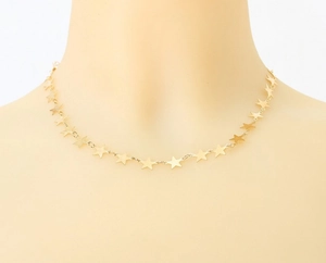 Detail of a gold multi-star pendant necklace on a model showing the layered link design