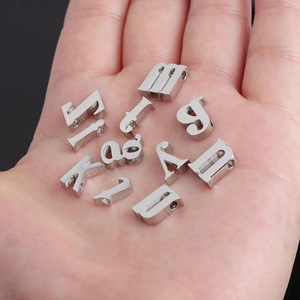 Macro view of 10mm mirror polished stainless steel alphabet beads in a palm