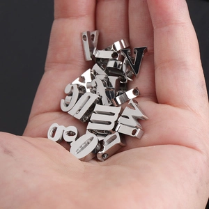 Macro view of 10mm mirror polished stainless steel alphabet beads held in hand