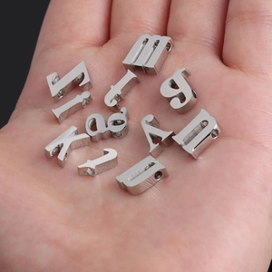 Polished 10mm stainless steel alphabet beads with small holes held in palm