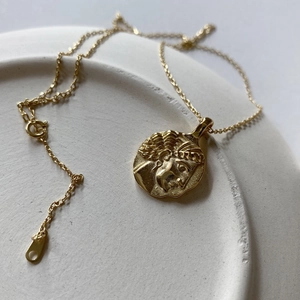 Detail of a 925 silver gold-plated coin necklace with a classical embossed portrait pendant