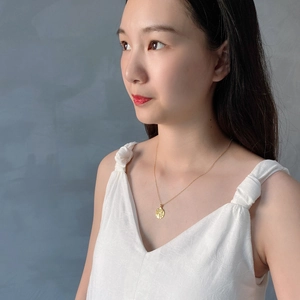 Detail of a 925 sterling silver golden coin pendant necklace worn by a female model