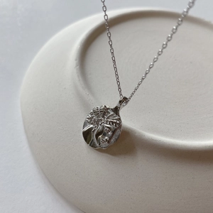 Close-up detail of silver vintage portrait medallion pendant on a fine cross chain