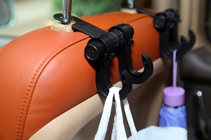 Dual car headrest hooks holding a white shopping bag and a purple umbrella in a car