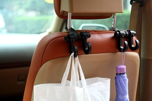 Dual car seat headrest hooks in black ABS plastic holding a shopping bag and umbrella
