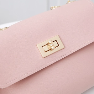 Close-up of pale pink PU leather phone bag with golden rotary lock and stitching