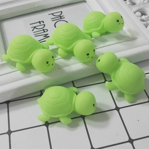 Close-up of five cute green rubber turtle squishy toys on a decorative photo frame