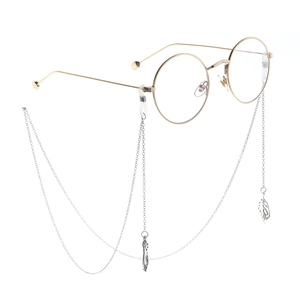 Detailed close-up of a gold round eyewear frame with a silver feather pendant chain