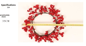Détail d'une couronne de Noël aux baies rouges de 35 cm mesurée avec un ruban à mesurer jaune