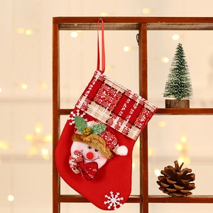 Red Christmas stocking with Santa doll and plaid cuff hanging as festive decoration