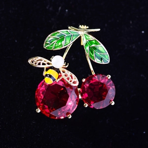 Enamel red cherry brooch with golden leaves and a bee accent on black background