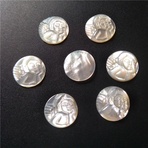 Macro view of seven natural mother of pearl angel relief charms on a dark surface