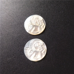 Macro shot of circular white mother of pearl pendants with carved angel reliefs