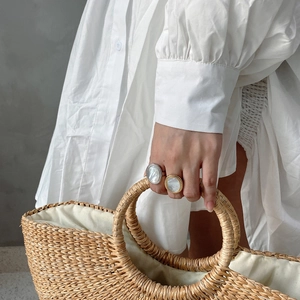 Close-up of minimalist oval shell rings in gold and silver on model hand