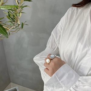 Close-up of gold and silver shell rings on model hands with leaf background
