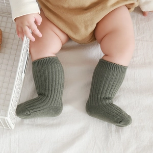Army green thick fleece-lined baby cotton socks worn by a toddler on a white fabric background