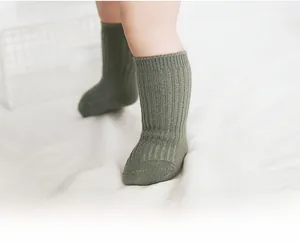 Detail of army green ribbed baby socks on infant legs showing texture and stretch