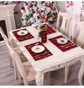 Christmas table setting with red and black plaid placemats and festive wine bottle cover