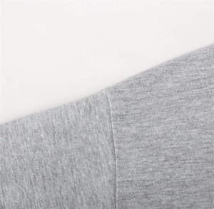Close-up of high-quality stitching and light grey knit fabric on casual lounge set