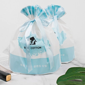 Detail of B COTTON cleansing towels in blue and white drawstring bags on marble surface