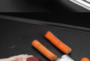 Gros plan d'une pince tenant du crabe et du bacon sur une poêle à griller en acier noir