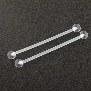 Close-up of two transparent acrylic barbell body piercing studs on a matte black surface