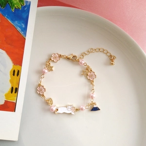 Detailed shot of cat and Mount Fuji charms on a pink cherry blossom pearl bracelet