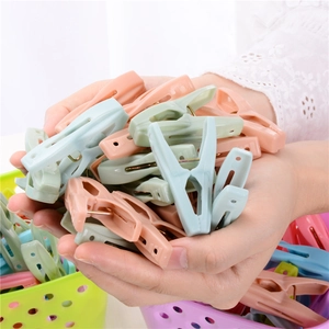 Main tenant un lot de 30 pinces à linge colorées en plastique avec panier de rangement