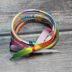 Close-up of rainbow glitter silicone bracelets with multi-color shimmer and silk ribbon