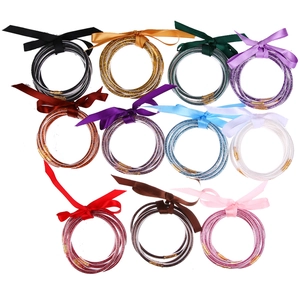 Detail of 11 glitter-filled jelly silicone bangles with matching satin ribbon bows