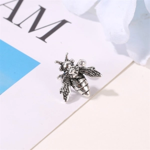 Macro shot of vintage silver bee ear cuff showing detailed texture on a floral background