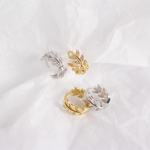 Macro shot of gold and silver olive leaf stud earrings with sparkling cubic zirconia stones