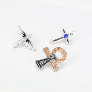 Détails macro de broches religieuses en métal avec croix ailes et émail coloré