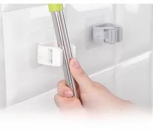 Detail showing wall-mounted holder with gravity grip mechanism holding a metal mop handle