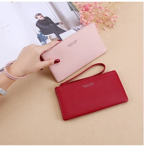 Litchi pattern leather long wallets in pink and red with wrist straps on a desk