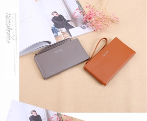 Detail of leather wristlet wallets with golden zippers in grey and caramel brown tones