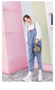 Fashionable denim overalls paired with a chic animal print handbag in urban setting